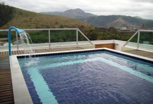 a large swimming pool with a water fountain at Green Valley Hotel in Acesita