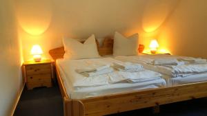 una camera da letto con un letto con lenzuola e cuscini bianchi di -"Große Koje" Fewo im OG - Fischländer Weg 53A a Dierhagen
