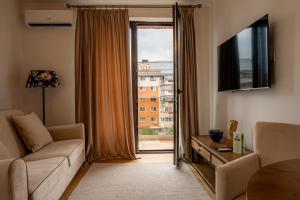 a living room with a couch and a large window at Aria Suites in Târgovişte