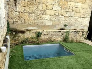 ein Pool im Gras neben einer Ziegelmauer in der Unterkunft Loft Bordeaux Près du Tram in Bordeaux