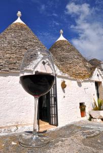 un bicchiere di vino rosso seduto di fronte a un edificio di Masseria Rosa Trulli Relais ad Alberobello