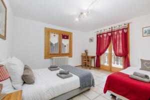 レ・ジェにあるAppartement Azalees 1の赤いカーテンの部屋にベッドが2つある