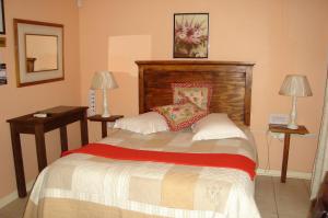 ein Schlafzimmer mit einem Bett mit zwei Tischen und zwei Lampen in der Unterkunft Taunton House B&B in Pietermaritzburg