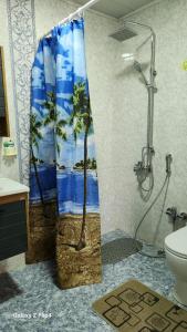 a bathroom with a shower with a palm tree shower curtain at Pine house in Gürgan