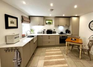 a kitchen with white counters and a table in it at Flower Cottage by Ludlow Castle with Onsite Parking in Ludlow