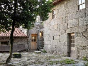a stone building with a door and a tree at Levada da Breca - Turismo Rural in Ervedeiros