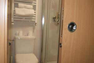 a bathroom with a toilet and a shower with towels at Habitaciones El Escorial in Majadahonda