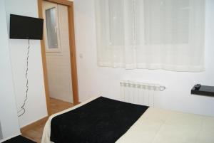ein Schlafzimmer mit einem Bett mit einer schwarzen Decke und einem Fenster in der Unterkunft Habitaciones El Escorial in Majadahonda