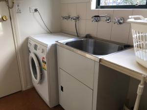 a small kitchen with a sink and a washing machine at Auburn Hideaway in Auburn