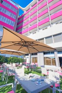 uma mesa com um guarda-chuva em frente a um edifício em SenB Hotel em Senigallia