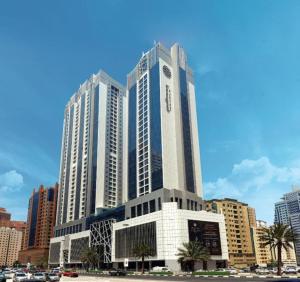a tall building with a clock on it in a city at Pullman Sharjah in Sharjah