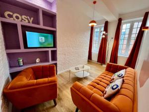 a living room with two couches and a flat screen tv at Les Seventies in Dieppe