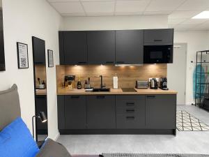 a kitchen with black cabinets and a counter top at SweetHome - Studio Apartment Ergolding in Ergolding
