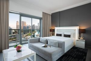 a bedroom with a bed and a couch and a large window at The First Collection Dubai Marina in Dubai