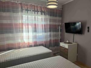 a bedroom with a bed and a tv and a curtain at Appartements Bel Lago Bestensee in Bestensee