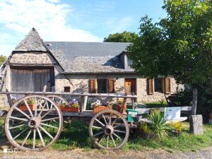 an old wagon in front of a stone house at Gîtes du GRC in Campuac