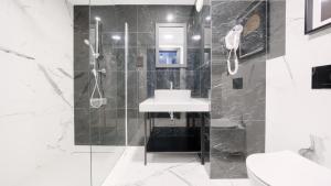 ein schwarz-weißes Badezimmer mit Waschbecken und Dusche in der Unterkunft Solny Resort, Sun & Snow in Kołobrzeg