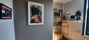 a hallway with a book shelf and a picture on the wall at Maison du jardin botanique 7 min centre et Gare Accueil Vélos in Tourcoing