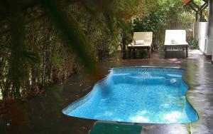 a swimming pool in the rain with a table and chairs at Niraamaya Wellness Retreats, Surya Samudra, Kovalam in Kovalam
