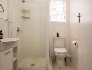 a white bathroom with a toilet and a shower at Withuis Hartenbos - No Load Shedding in Hartenbos +87 photos