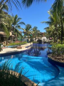 a pool at the resort with palm trees at Cobertura Parque das Ilhas in Mangabeira