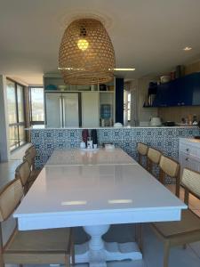a kitchen with a large white table and chairs at Cobertura Parque das Ilhas in Mangabeira