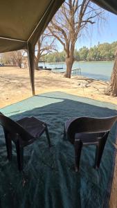 ChristianaにあるRiverbend Camp - Panache Family Tent with Private Ablutionの地面にテーブルと椅子が置かれたテント