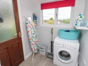 a laundry room with a washing machine and a window at Crosby Cottage in Wooler