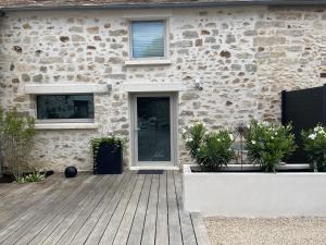 a stone house with a wooden porch with potted plants at Le Passage Secret in Fleury-en-Bière