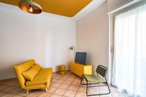 a living room with a yellow chair and a television at Aosta Holiday Apartments - Promis in Aosta