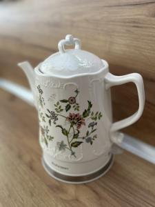 a white teapot with flowers on it sitting on a table at Trinity House in Obrochishte