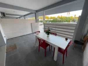 a dining room with a white table and red chairs at Pegaso B&B in Ippocampo