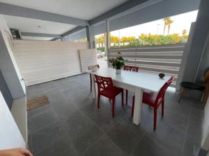 a dining room with a white table and red chairs at Pegaso B&B in Ippocampo