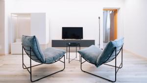アオスタにあるAosta Holiday Apartments - Piazza Chanouxの椅子2脚とテレビのあるリビングルーム