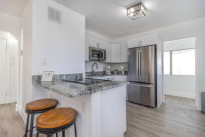 a kitchen with a stainless steel refrigerator and two bar stools at New Cozy 2BR heart of Tampa in Tampa