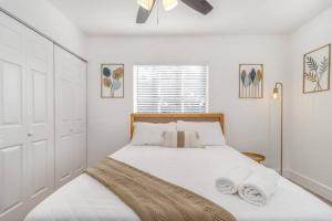 a white bedroom with a bed with towels on it at New Cozy 2BR heart of Tampa in Tampa