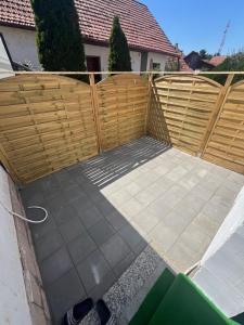a backyard with a wooden fence and a sidewalk at Apartman Uno in Kikinda