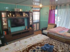 a living room with two beds and a television at Lebong Mansara Homestay in Darjeeling