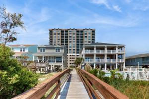 a wooden boardwalk leading to a beach with houses at Beachwalk Villas 803 in Myrtle Beach