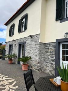 ein Gebäude mit einer Bank und Pflanzen davor in der Unterkunft Guest House Santinhos in Estreito da Calheta