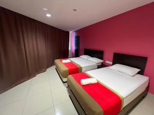 two beds in a room with a red wall at Hotel Crystal Villa in Kampong Batu Enam
