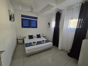 a white bedroom with a bed and a window at Les Terrasses de la Wallon Cannelle in Les Trois-Îlets +6 photos