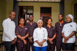 a group of men and women standing in a room at Hecasa Apartments in Arusha