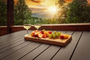 a cutting board with fruit and two glasses of wine at Mountain View, Indoor Pool, Luxury Cabin, Bears in Gatlinburg