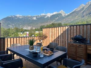 a table on a deck with a view of mountains at Lux Apartment in Bovec