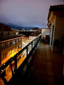 Un balcón con vista a una ciudad de noche. en Precioso ático con amplia terraza, en Portonovo