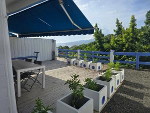 a deck with a table and a blue umbrella at Les Terrasses de la Wallon Cannelle in Les Trois-Îlets
