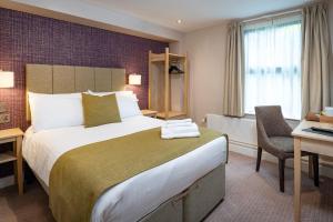 a hotel room with a large bed and a desk at Lydiard Park Hotel in Swindon