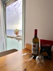 a bottle of wine sitting on a table with a glass at Apartamento costero, los Abrigos. in Los Abrigos