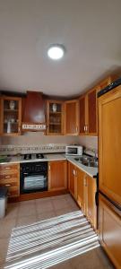 a kitchen with wooden cabinets and a stove top oven at Casa Rural Fuente del Céfano in Arroyo Frio